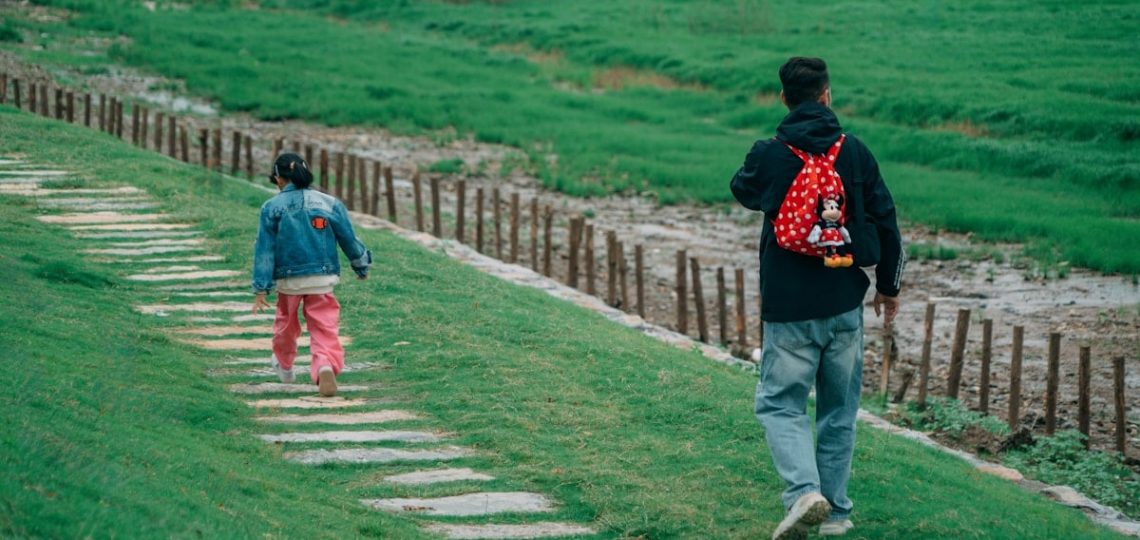 A couple of people walking down a grass covered hillside