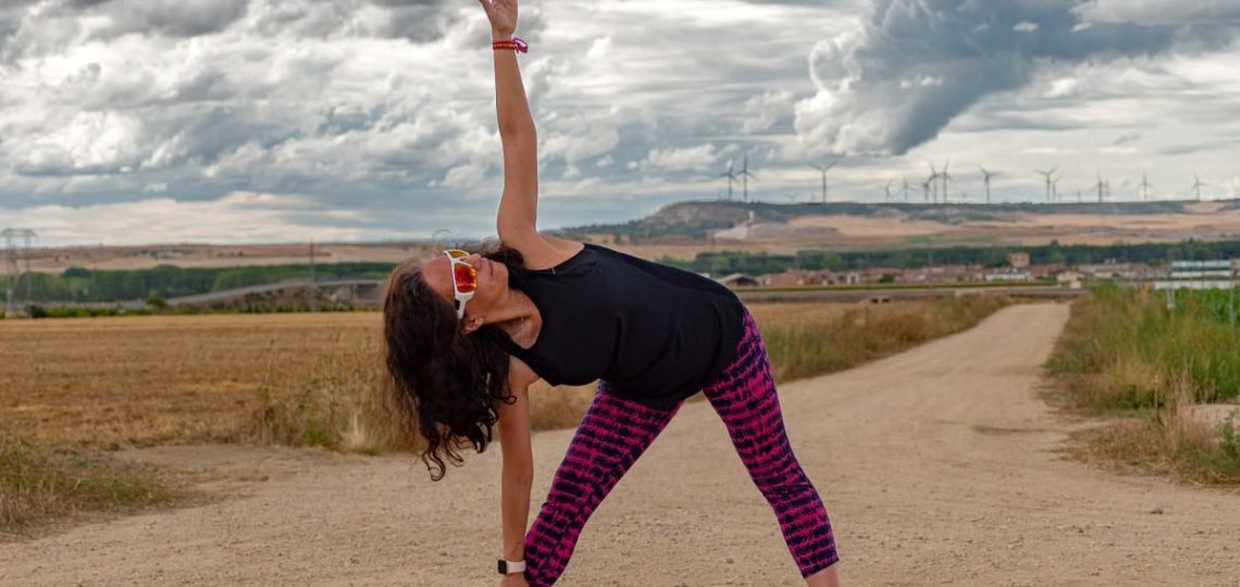Outdoor fitness scene of a woman stretching on a dirt path in Soto de Cerrato amidst scenic landscapes.